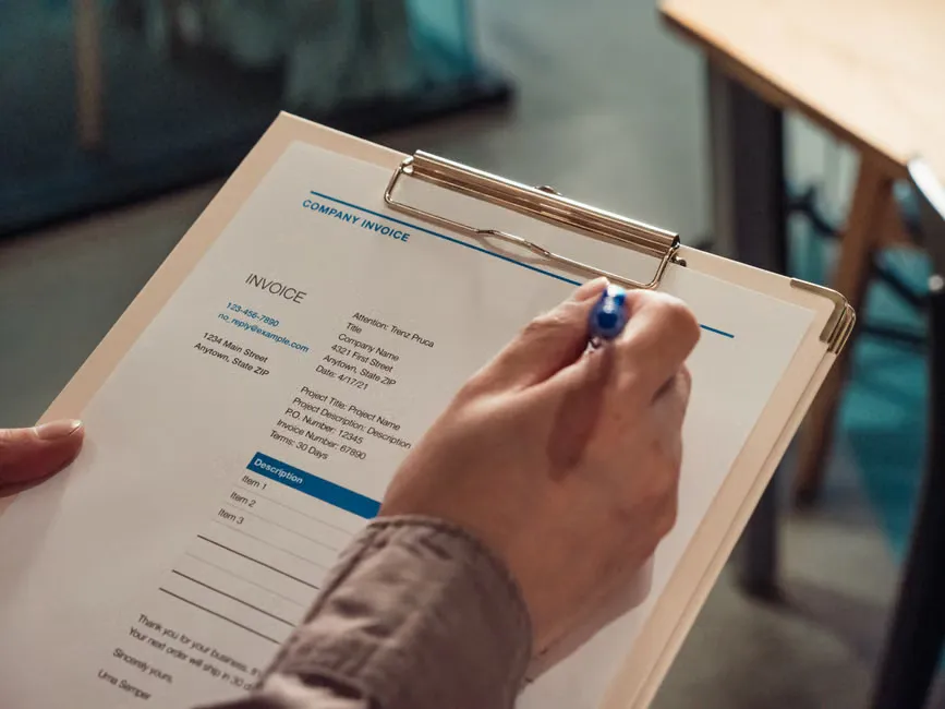 A printed invoice on a desk with the GST total circled in pencil